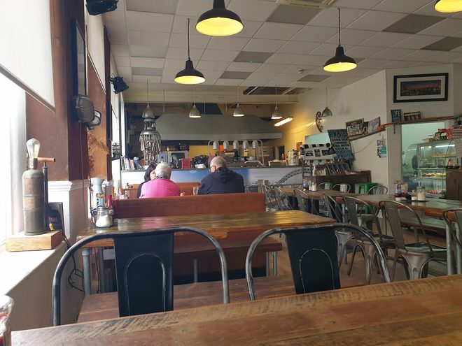 The room under its pendant lights with diners seated at the far end