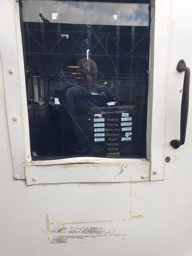 The cafe's white entrance door with its dark glass panel and worn paintwork