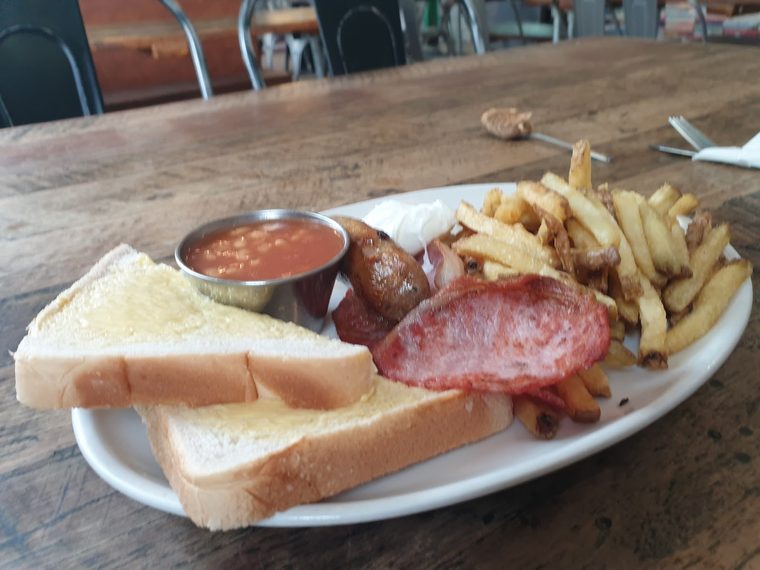 Breakfast plate of sausage, bacon, chips, beans and toast