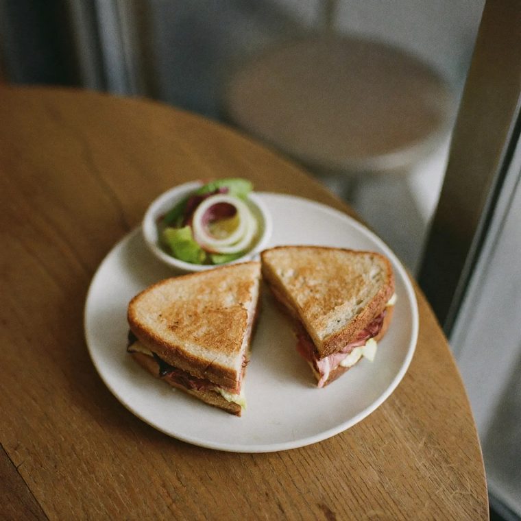 A toasted sandwich cut in half with a side salad
